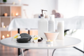 Massage stones with cosmetics products on table in spa salon