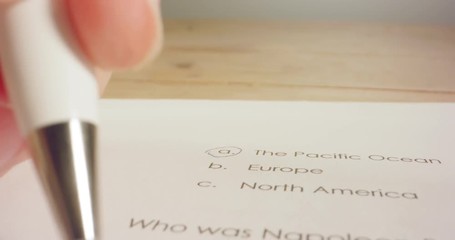 Tracking macro shot of pen marking answers in a history test in school