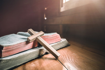 Close up wooden cross on bible with light in morning. christian concept.