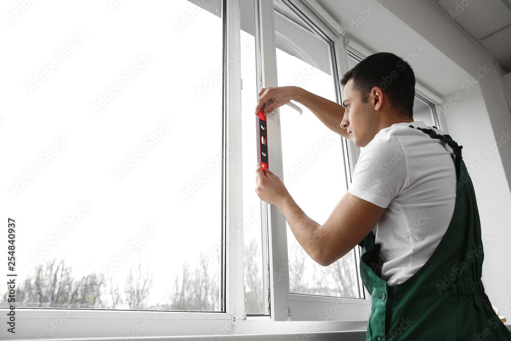 Wall mural young worker repairing window in flat