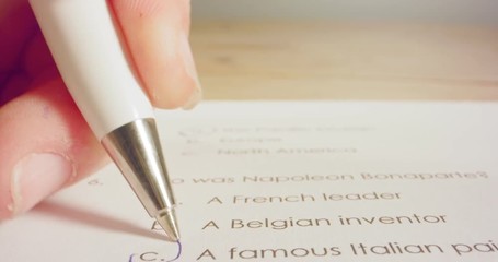 Tracking macro shot of pen marking answers in a history test in school