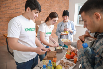 Young volunteers giving food to poor people