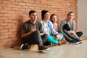 Poor people with products received from volunteers sitting near brick wall