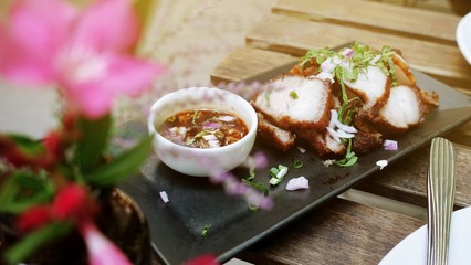 Deep Fried Crispy Pork Belly Cooked with Garlic and spicy dipping sauce on wooden table background.