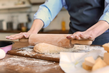 Obraz na płótnie Canvas Beautiful woman making dough in kitchen at home, closeup