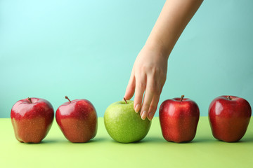 Female hand with tasty apples on color background. Concept of uniqueness