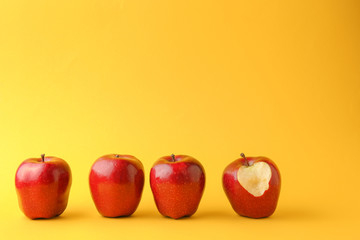 Bitten apple among whole ones on color background. Concept of uniqueness