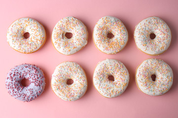 Lilac doughnut among white ones on color background. Concept of uniqueness