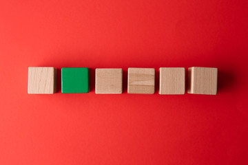 Green cube among wooden ones on color background. Concept of uniqueness
