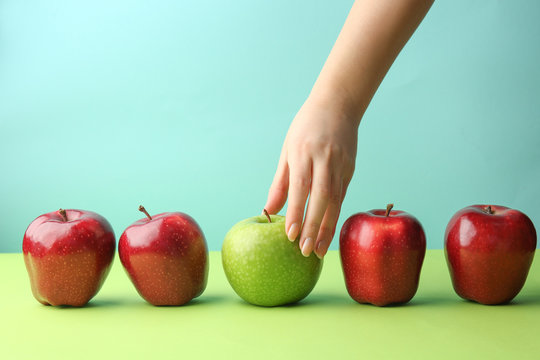 Female hand with tasty apples on color background. Concept of uniqueness