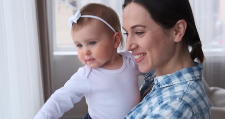 Happy mother with curious baby girl at home