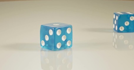 Slow motion macro shot of dice falling and rolling on reflective surface