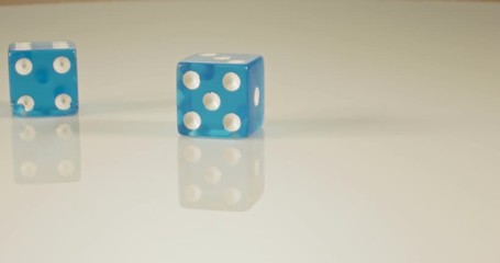Slow motion macro shot of dice falling and rolling on reflective surface