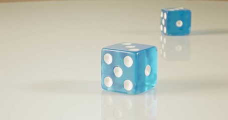 Slow motion macro shot of dice falling and rolling on reflective surface