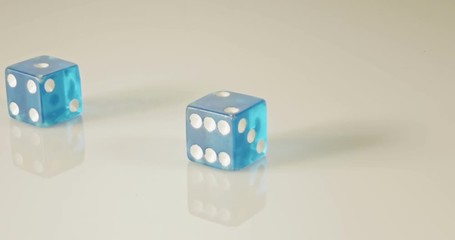 Slow motion macro shot of dice falling and rolling on reflective surface