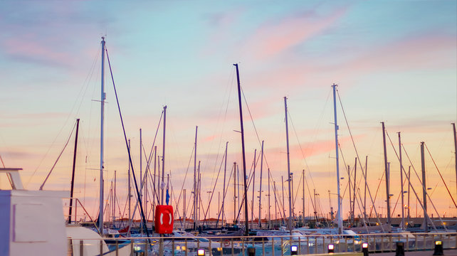 Scenic picture of the silhouettes of yacht masts against the blue and pink sunset sky on the Mediterranean coast in the port of the Spanish city