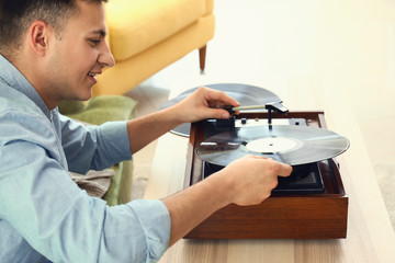 Young man listening to music on record player at home