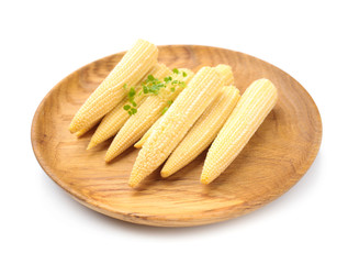 Plate with baby corn cobs on white background