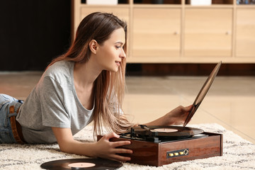 Young woman with old record player and vinyl discs at home