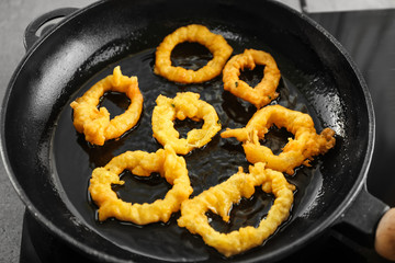 Cooking of tasty onion rings in frying pan, closeup