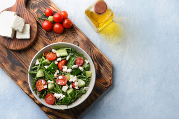 Healthy salad with feta cheese on light table