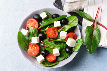 Healthy salad with feta cheese on light table