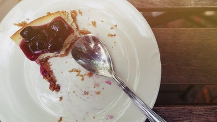 Empty white plate with spoon after dessert cake on wood table background Perspective view of empty dirty plate or dish, and waste food after eaten, dirty dish after finish meal.