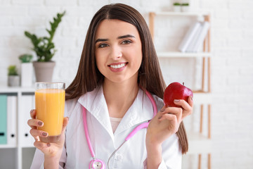 Portrait of female nutritionist with glass of juice and apple in her office