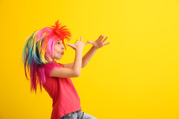 Funny little girl in wig on color background. April fools' day celebration - obrazy, fototapety, plakaty