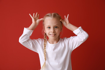 Funny grimacing little girl on color background