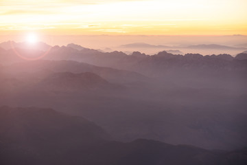 Foggy morning in Italian Alps mountains. Mountain range silhouttes aerial view.