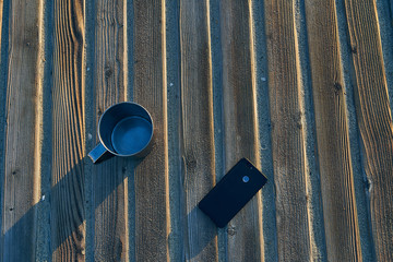 metal mug mobile phone lying on a tree-based basis on the seafront 