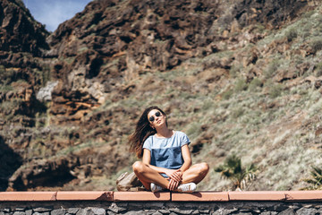 Happy pretty tourist brunette girl relaxing near rock.