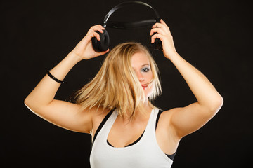 Blonde woman holding big headphones in studio