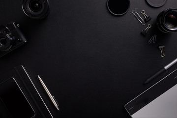 Top view of the black table graphic designer with camera, lenses and diary with copy space. Flat lay shot