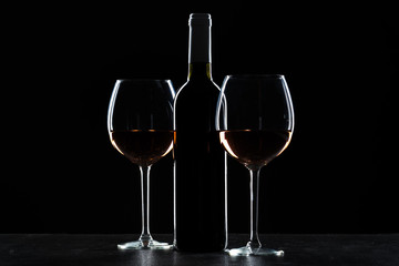 Bottles of wine and different glasses of wine on a dark background