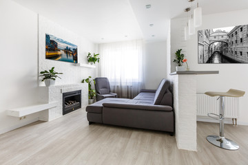 Flower on wide wall art canvas. Sofa, lamp, plant and table in room interior.