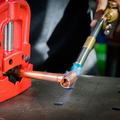  In the workshop, connecting copper pipes with a burner