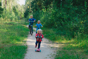 Obraz premium happy active kids on bike and scooter ride in nature