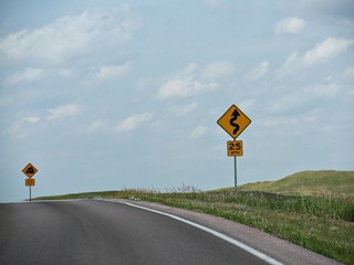 Road signs warning motorists of a curve and dangerous slope with road grade percentage