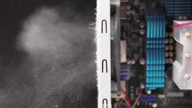 Side view of man using compressed air and blowing dust and dirt from metal case of computer