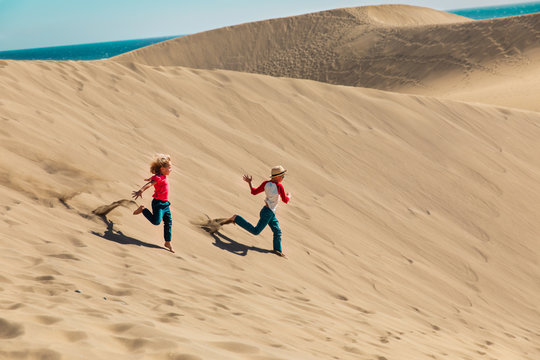 happy boy and girl play in sand dunes