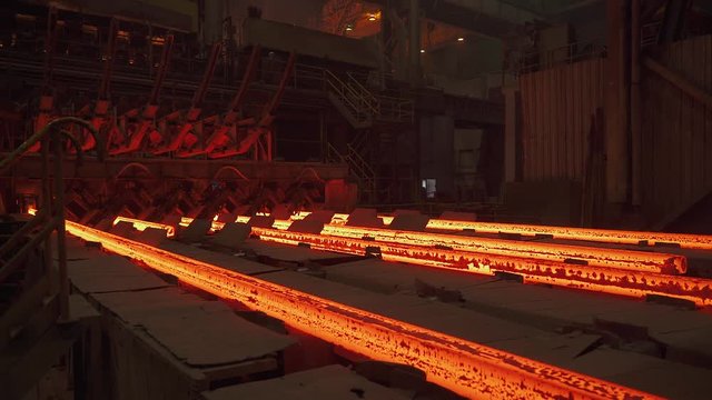 Steel mill, steel bars and pipe production, red-hot pipes transported on production line, heavy industry, rolled metal factory.