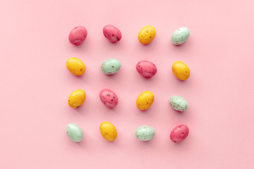 Easter chocolate eggs candy on a pastel pink background, creative flat lay easter concept, top view