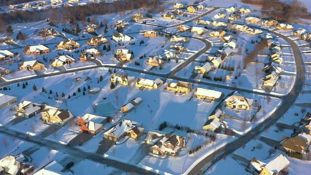 Aerial view of perfect, wealthy neighborhood with snow covered rooftops in the stunning light of  Winter sunrise.
