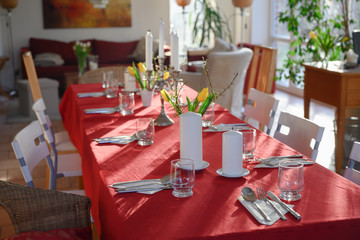 improvised dining table for many guests with red tablecloth and decoration in the living room
