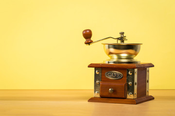 Vintage manual coffee grinder on wooden table with color wall background