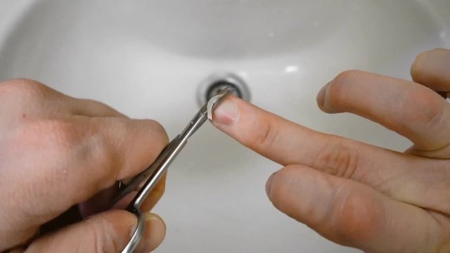Timelapse man cuts his nail by scissors over sink in bathroom in the morning
