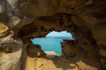 Sandstone rock with hole and blue sea in it