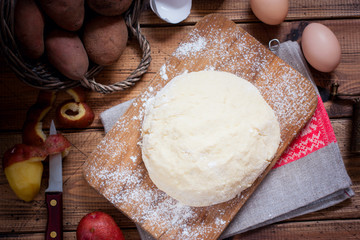 Raw potato dough on a wooden board, top view